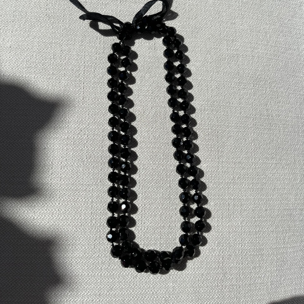 Black glass bead necklace with bow for clasp.